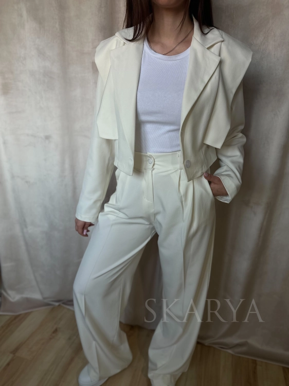 Kremowy ecru elegancki komplet. Krótka marynarka z podkreśloną linią ramion zapinana na guzik. Spodnie na gumce z szeroką nogawką typu wide leg, szlufki na pasek, kieszenie, lekki zwiewny materiał. Idealny na wyjątkowe okazje jak i na co dzień.