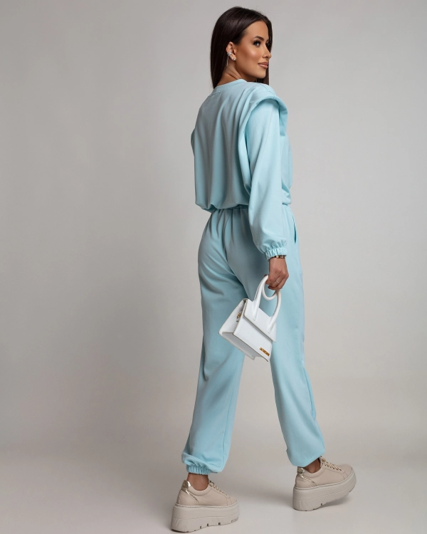 Niebieski komplet dresowy damski. Bluza typu crop regulowana ściągaczem, z poduszkami na ramionach. Spodnie typu jogger ze ściągaczem na nogawkach. Nietypowy dres, który łączy w sobie wygodę i modowy charakter. Wykonany z miękkiego w dotyku materiału.